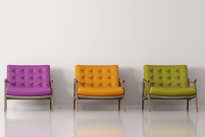 Drei farbige Stühle an der Wand