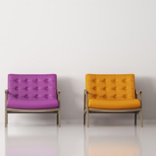 Drei farbige Stühle an der Wand